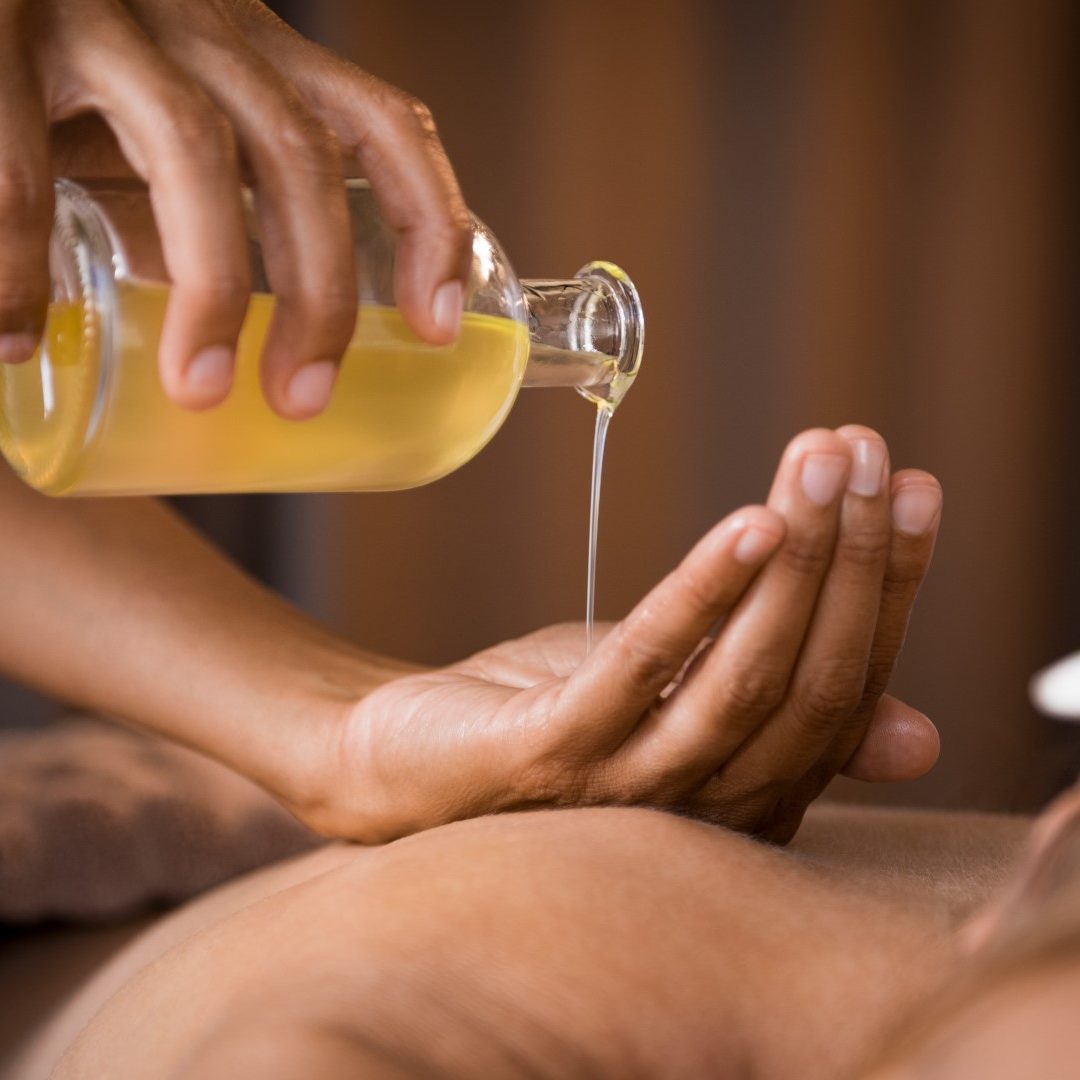 Therapist pouring massage oil at spa Closeup of masseur hands pouring aroma oil on woman back. Masseuse prepare to do oriental spa procedure for relaxing treatment. Therapist doing aromatherapy oil massage on woman body.